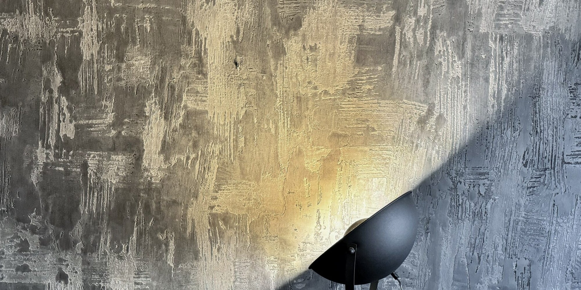Effektbeschichtete Wand mit Gold- und Grauverlauf im Streiflicht